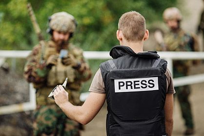 A journalist in a black bulletproof vest presents documents to a patrol